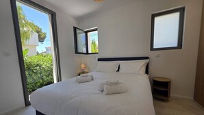 Una camera da letto con un letto grande, un comodino, un tavolino, una finestra e vista sul verde.