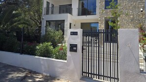Un edificio moderno su due piani, con facciata in pietra, ingresso carrabile e un balcone.