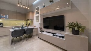 A modern kitchen with a large TV, dining area, and a potted plant. - St Francis of Assisi Superior Budapest (Budapest)