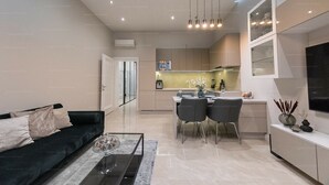 A modern living room with a sofa, coffee table, and dining area with chairs and a table. - St Francis of Assisi Superior Budapest (Budapest)