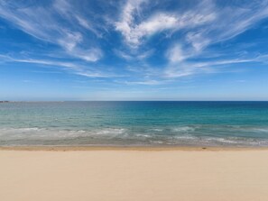 Ein Strand mit blauem Himmel und ruhigem Wasser.
