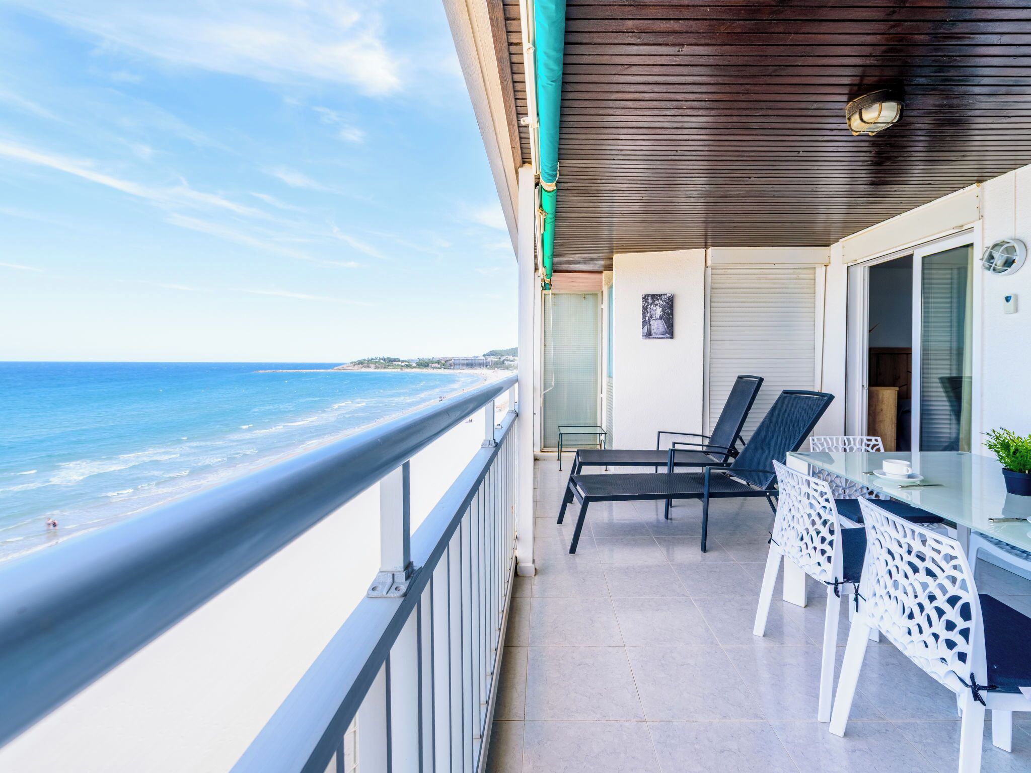 Un balcon avec vue sur la plage, une table avec des chaises et une plante en pot.
