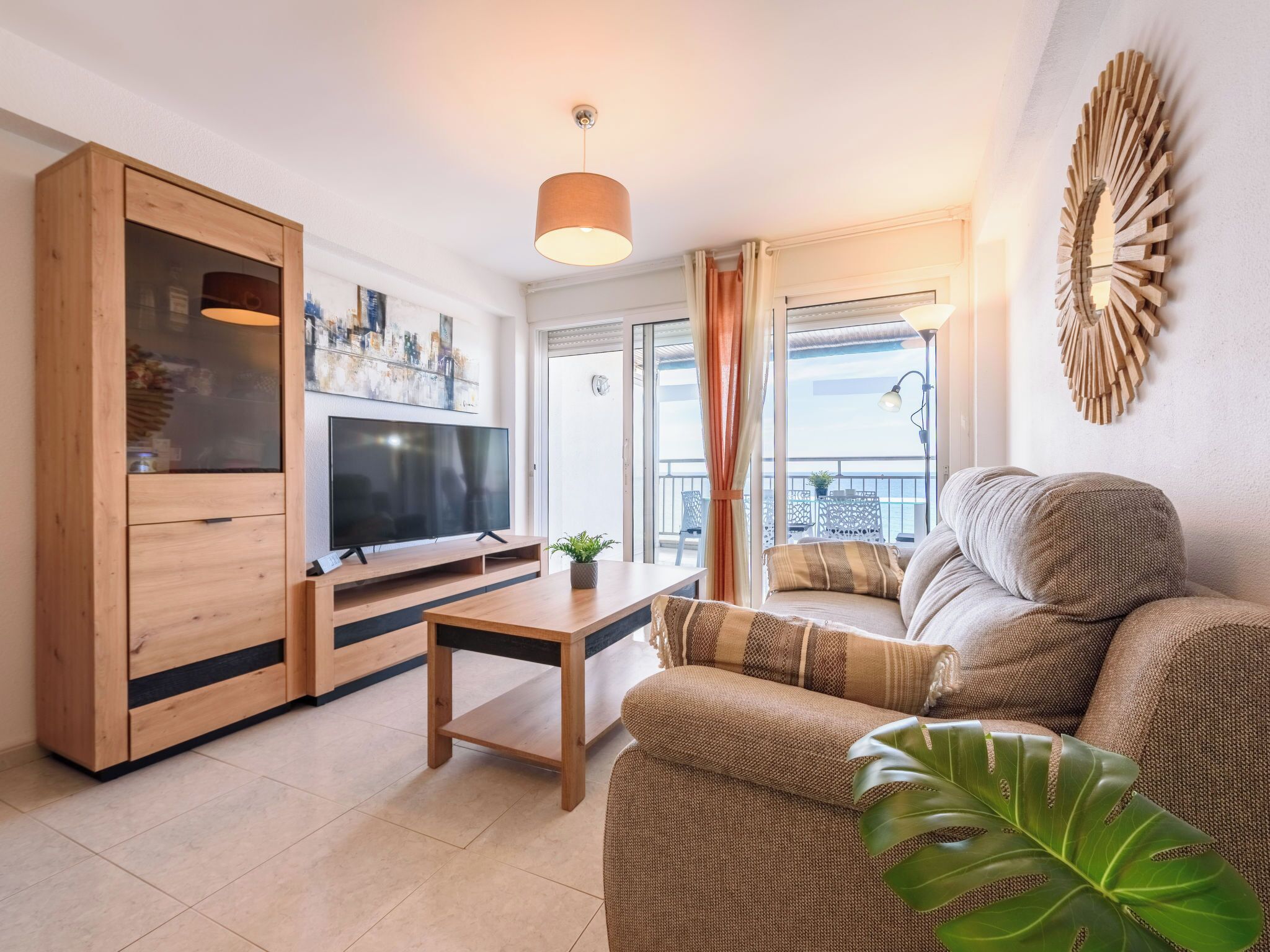 A living room with a TV, wooden cabinet, sofa, and a potted plant.