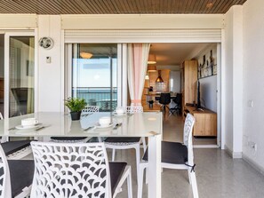 Ein moderner Essbereich mit einem Glastisch, weißen Stühlen und Blick auf den Balkon.
