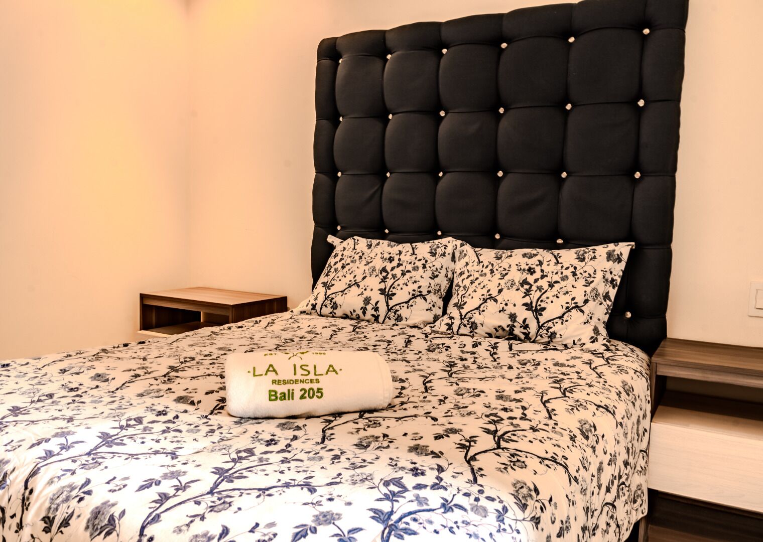 Un lit avec une couvre-lit à motifs floraux et un oreiller portant l’inscription « LA ISLA RESIDENCES Bali 205 ».