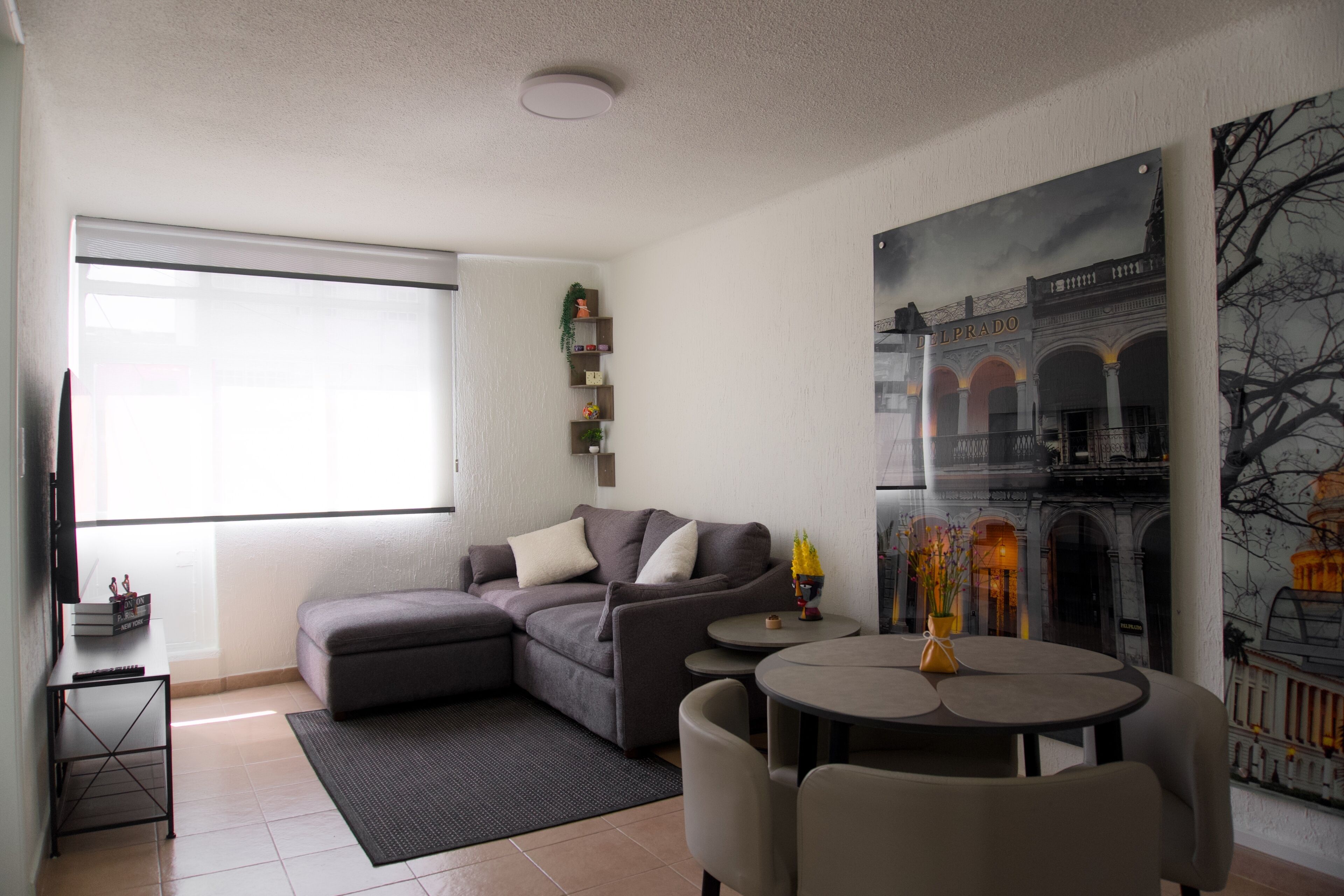 A living room with a sectional sofa, a round table, and a large window.
