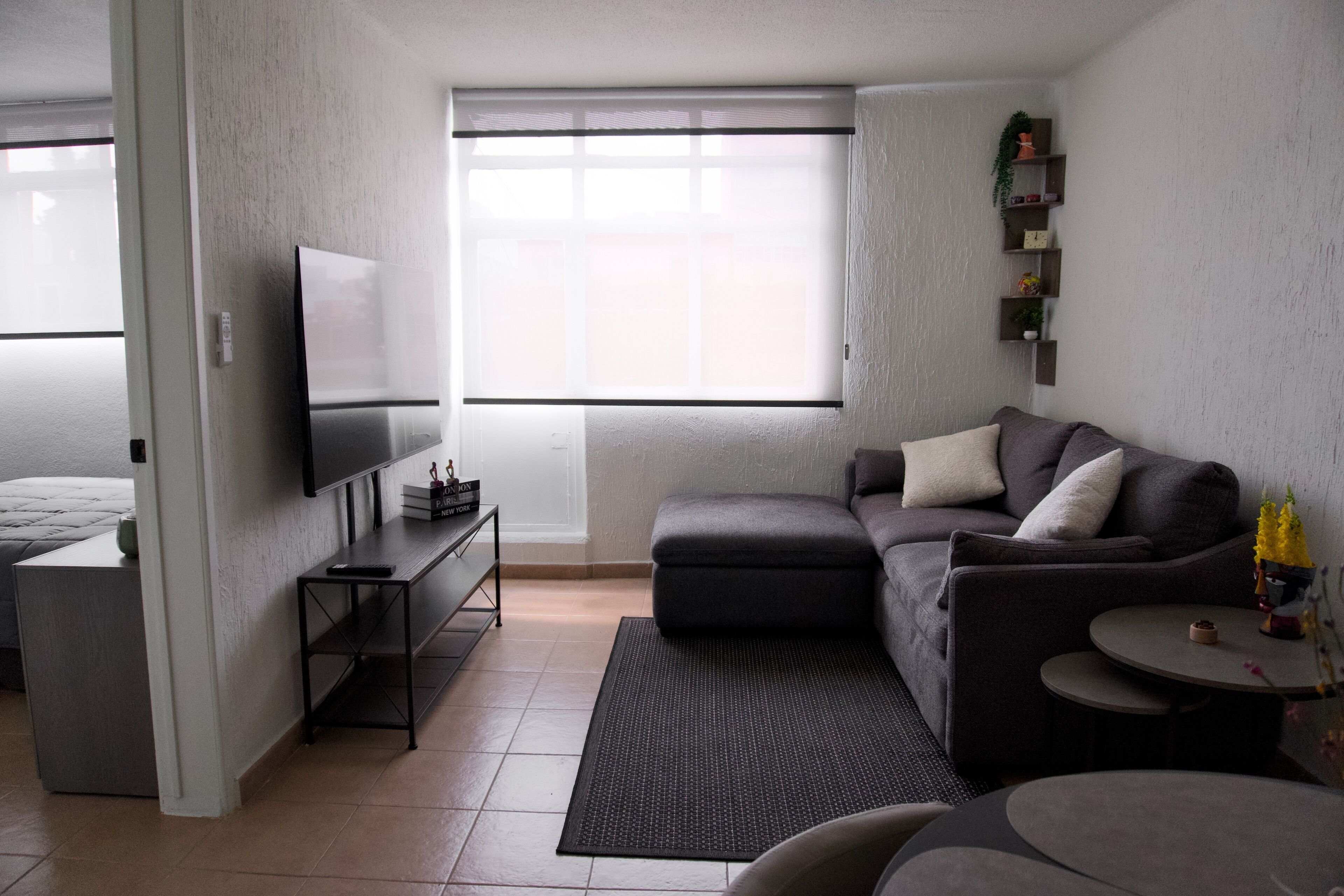A modern living room with a sectional sofa, a flat-screen TV, a small coffee table, and a side table.