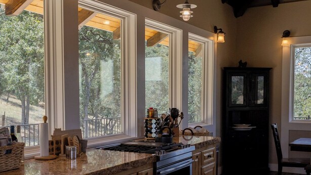 Una cocina con ventanas amplias, armarios de madera y encimera de granito.