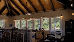 Una cocina amplia con barra, ventanas grandes y vigas de madera en el techo.