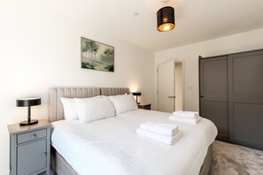 Ein Hotelzimmer mit Bett, Nachttischen, einem Gemälde, einem Kleiderschrank und einer Pendelleuchte.