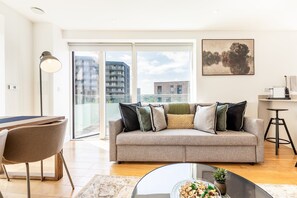 Ein modernes Wohnzimmer mit einer Couch, einem Esstisch und einem großen Fenster mit Blick auf die Stadt.