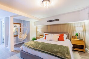 Ein modernes Schlafzimmer mit Bett, Nachttischen, einem Hängekorbstuhl und einem an der Wand befestigten Schild.