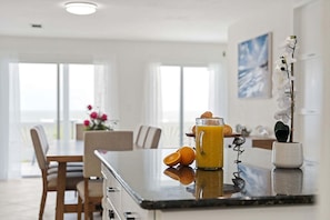 Eine moderne Küche mit Marmorarbeitsplatte, einem Glas mit Orangensaft und einer Topfpflanze mit Orchideen.