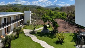 Un hotel con un patio, un camino y vistas a colinas y montañas verdes.