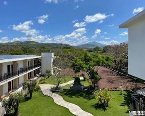 A hotel with a courtyard, a pathway, and a view of green hills and mountains. - Hotel Casa del Rio (Angel R. Cabada)
