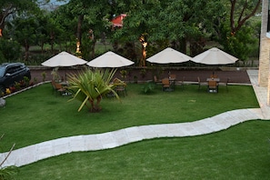 A well-maintained outdoor seating area with tables and chairs, surrounded by lush greenery and trees.