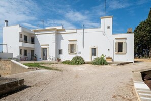 A white building with multiple windows, a bicycle, and a gravel driveway. - Apartment 'A Casa Di Legnointesta' with Private Terrace, Wi-Fi and Air Conditioning (Nardò)