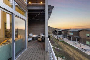 Ein Balkon mit Feuerstelle, Sitzgelegenheiten und Blick auf angrenzende Gebäude.