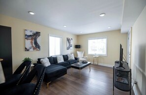 A modern living room with a sofa, armchairs, a coffee table, and artwork on the walls. - Queen City Hub (Cincinnati)