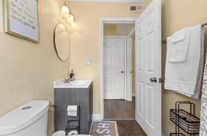 A bathroom with a toilet, sink, mirror, and towel rack. - Queen City Hub (Cincinnati)
