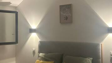 A bedroom with a bed, two bedside lamps, a wall-mounted artwork, and a door.
