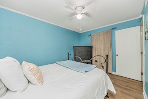 Ein Schlafzimmer mit einem Bett, einem Schminktisch, einem Kleiderschrank und einem Deckenventilator.
