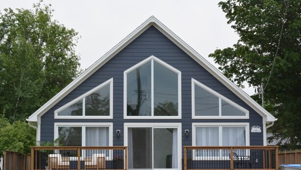 A two-story house with a dark blue exterior, white trim, and a large front window.