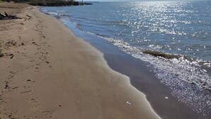 A beach with a clear sky, calm water, and a sandy shore.