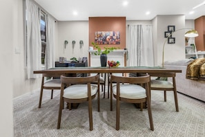 A dining area with a table, chairs, a vase with flowers, and a painting on the wall.
