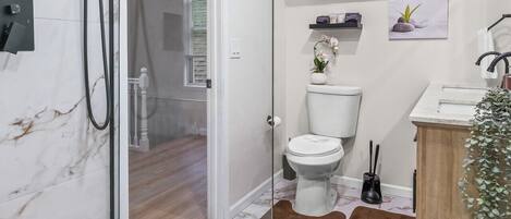 Une salle de bain moderne avec une douche à parois de verre, des toilettes et un lavabo.