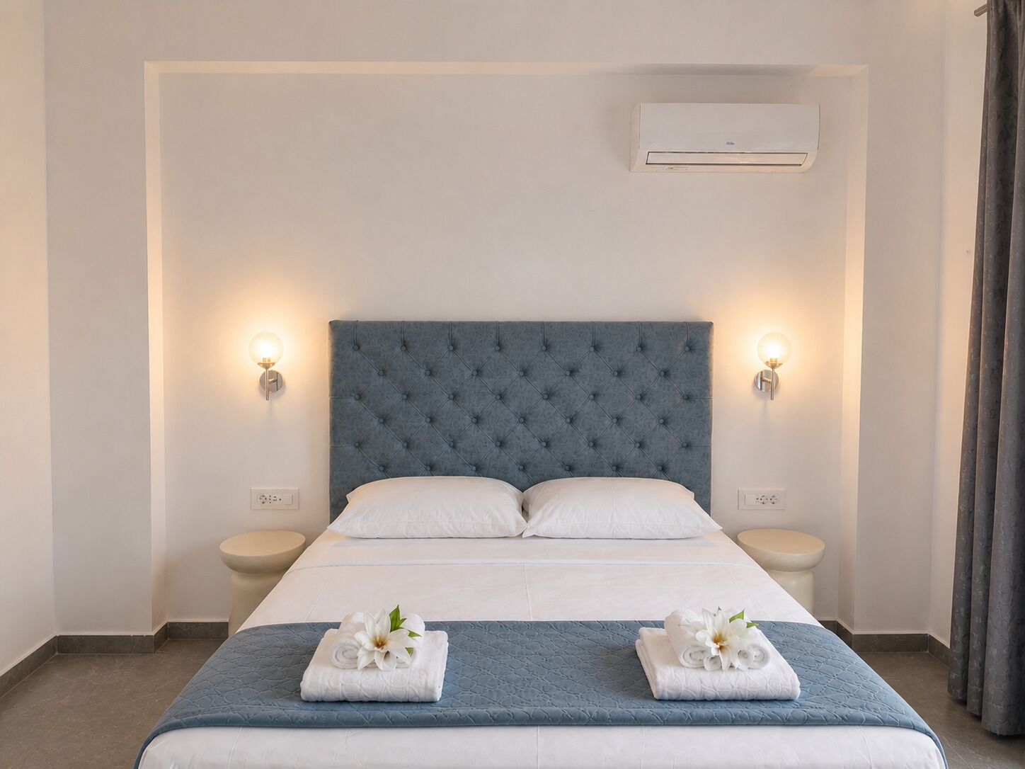 Ein Hotelzimmer mit einem großen Bett, zwei Nachttischen, einer Klimaanlage und einem Badezimmer mit Toilette und Waschbecken.