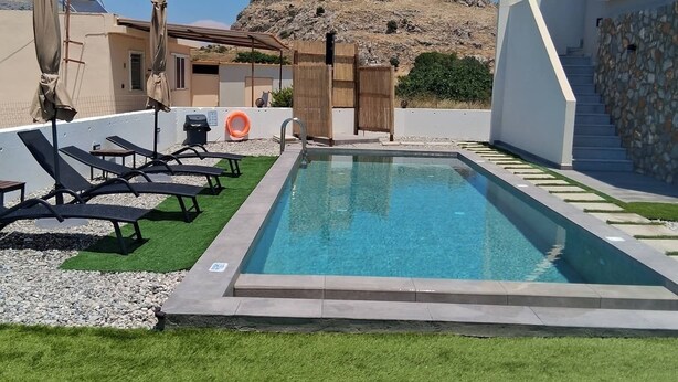 Ein Pool mit Liegestühlen und einer Steinmauer.