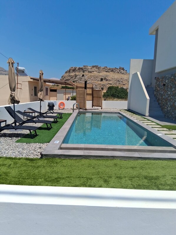 Ein Pool mit Liegestühlen und einer Steinmauer.