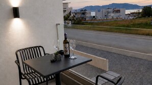 Ein Balkon mit Tisch und Stühlen, einer Weinflasche und Blick auf eine Straße und Gebäude.