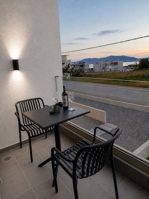 Ein Balkon mit Tisch und Stühlen, einer Weinflasche und Blick auf eine Straße und Gebäude.