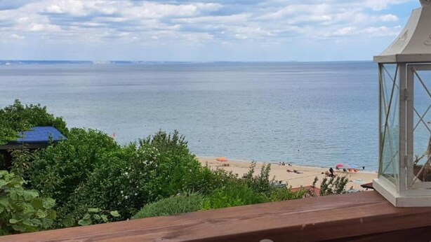 A view of a beach with a white lantern on a wooden railing.