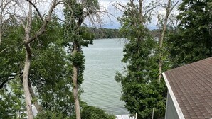 Un'area patio con tavolo e sedie, una zona relax coperta e vista su un corpo d'acqua.
