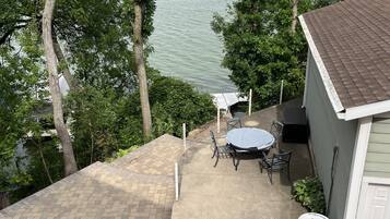 Een terras met tafel en stoelen, een overdekte zithoek en uitzicht op een waterpartij.