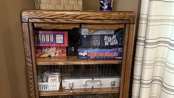 A wooden cabinet with various board games and a blue mug on top.