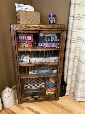 A wooden cabinet with various board games and a blue mug on top.