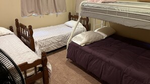 Una camera del dormitorio con due letti singoli, una cuccetta e una sedia.