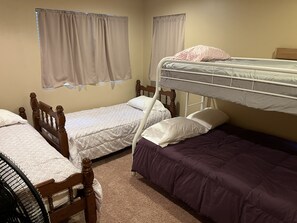 Een slaapzaal met twee eenpersoonsbedden, een stapelbed en een stoel.