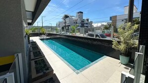 Una piscina con borde de azulejos, rodeada de un solárium alicatado.
