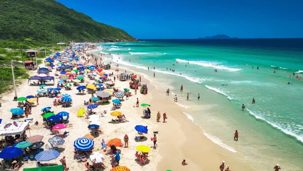 Una playa con muchas sombrillas y gente.