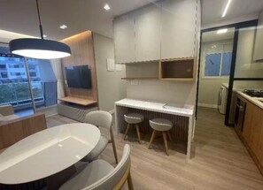 A modern kitchen with a dining area, a built-in bench, and a view of the outside. - New and cozy: on the beach and with a pool (Ingleses, Florianópolis) (Florianópolis)