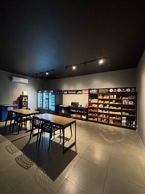 A room with a table and chairs, a vending machine, and shelves stocked with snacks.