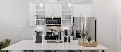 A modern kitchen with white cabinets, stainless steel appliances, and a central island with bar stools.