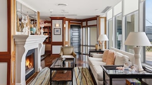 A spacious living room with a fireplace, a sofa, a coffee table, and a bookshelf. - Hi-Rise Condo W/ Beach Views & Resort Pool! (Galveston)