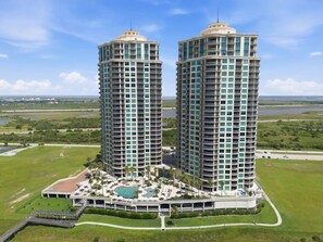 Two high-rise buildings with a swimming pool and lounge area in front. - Hi-Rise Condo W/ Beach Views & Resort Pool! (Galveston)