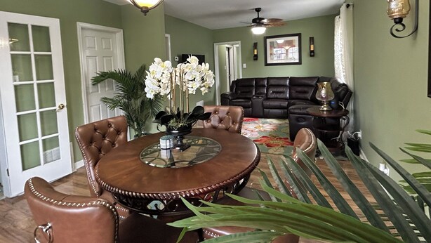 A dining area with a round table, chairs, a chandelier, and a sofa in the background. - Bright and Airy 3 BRM - 1 BATH -5 Mins to Falls (Niagara Falls)